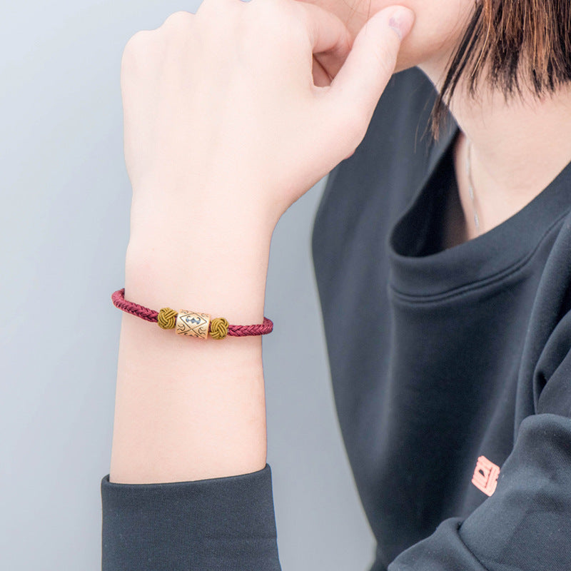 Le bracelet "Pareja" porté au poignet gauche par une femme qui porte un pull bleu marine