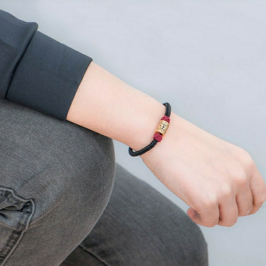 "Pareja" en noir porté au poignet droit avec un jean gris et un pull