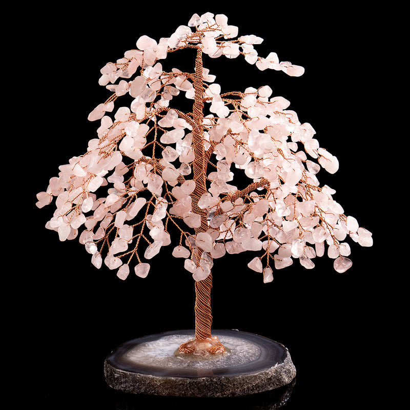 Arbre de vie décoratif avec des feuilles en quartz rose et un tronc en fil de cuivre torsadé, posé sur une base en agate grise et blanche.