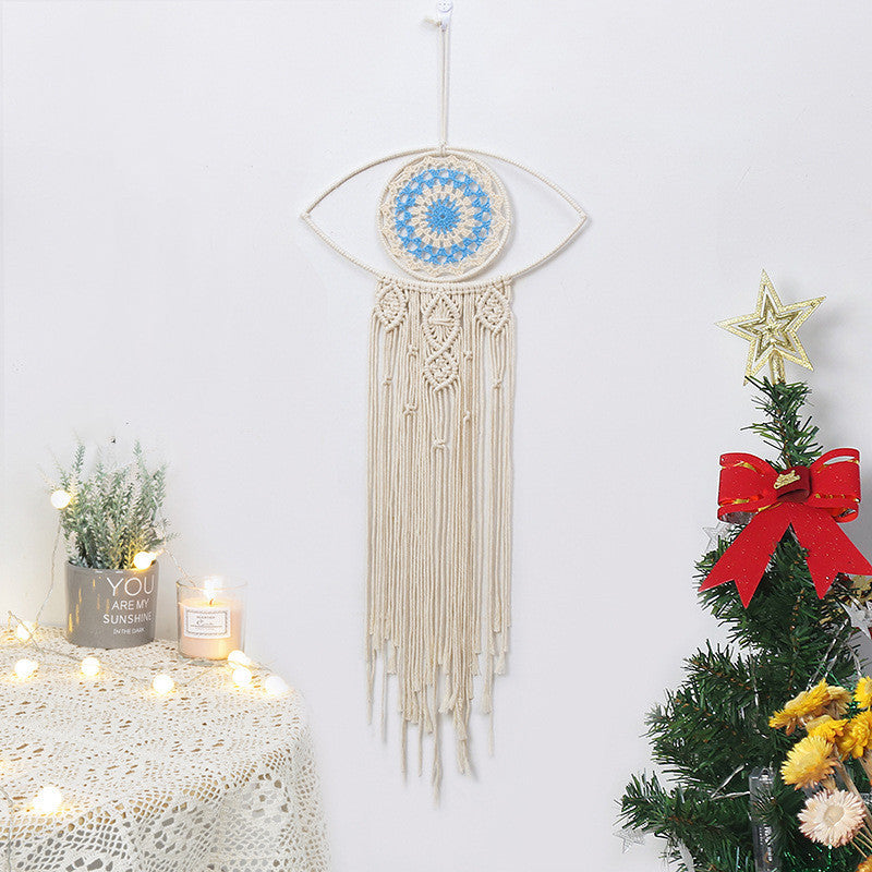 Attrape-rêves en macramé en forme d'œil avec des détails bleus et blancs et des franges suspendues, idéal pour la protection contre le mauvais œil.