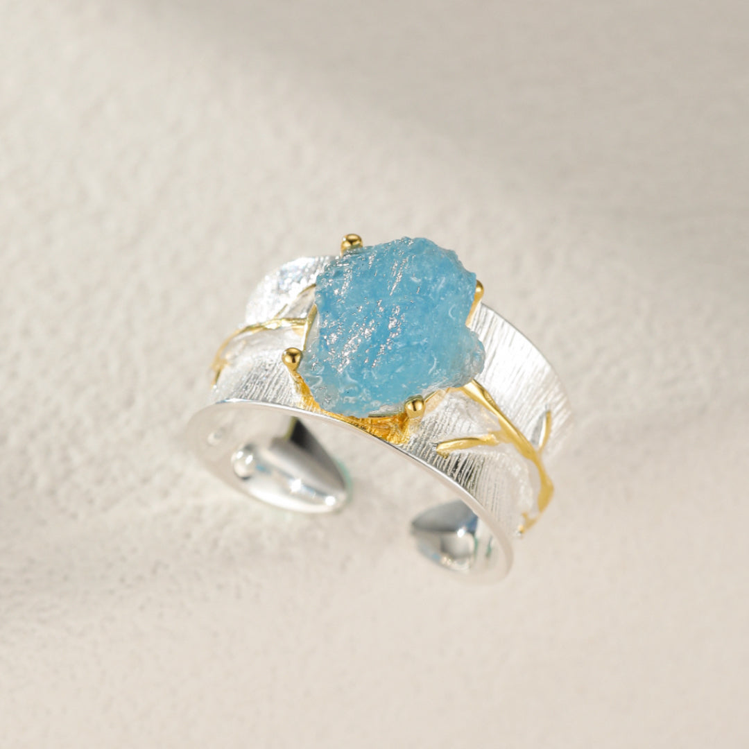 Bague ajustable en argent 925 avec une aigue-marine brute bleue lumineuse, design inspiré par la nature et les éléments marins.