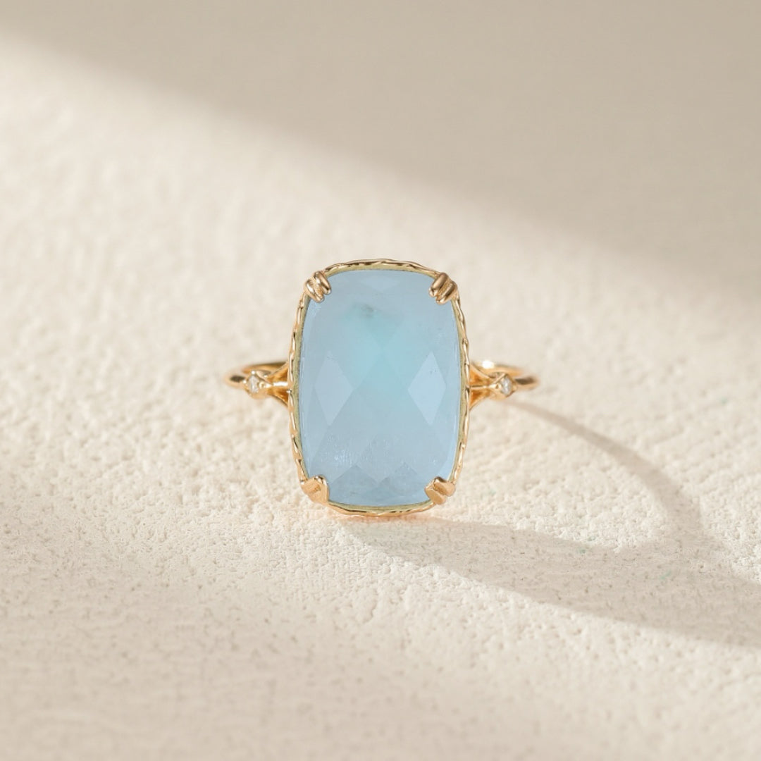 Bague en argent plaqué or sertie d'une aigue-marine rectangulaire facettée bleu pâle, ornée de deux petits diamants sur chaque épaulement.