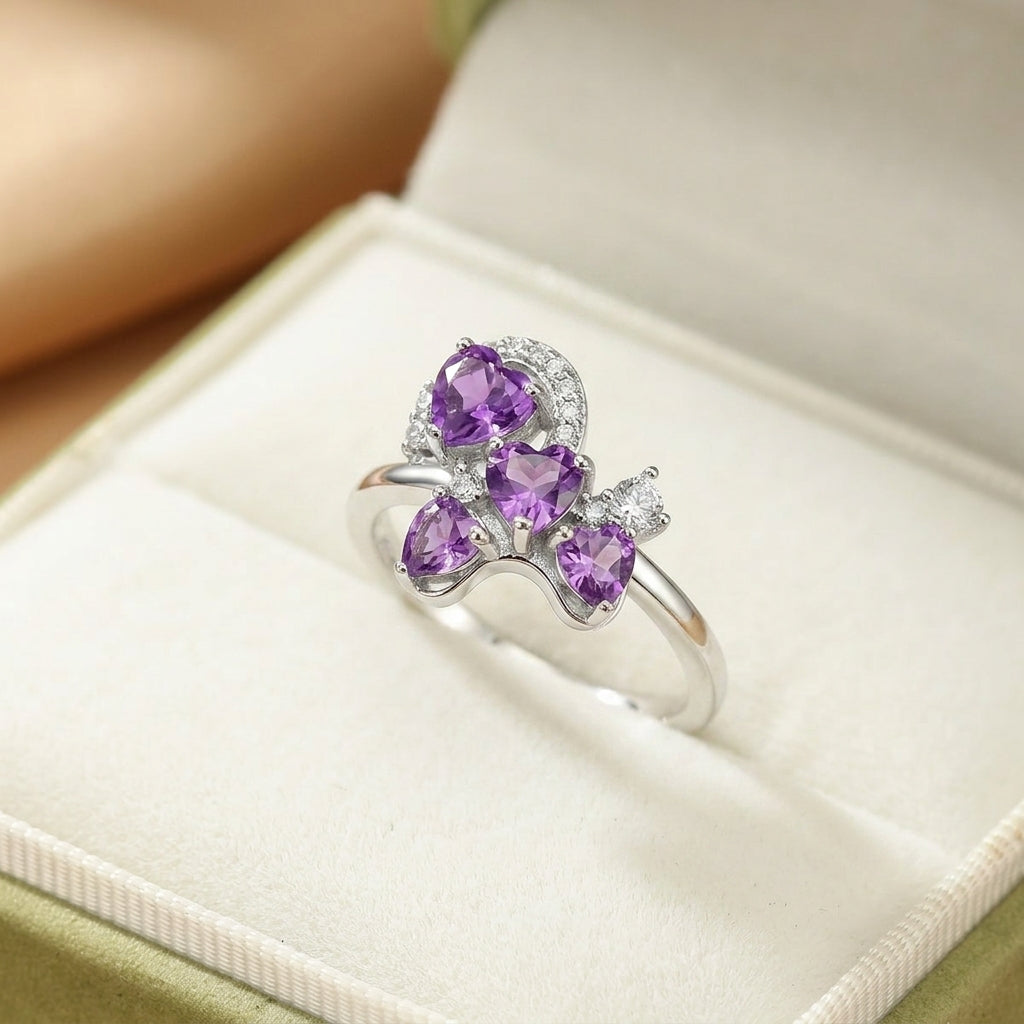 Bague en argent et plaqué or ornée d'améthystes en forme de cœur et de petits diamants, le tout dans un design rappelant un trèfle à quatre feuilles.