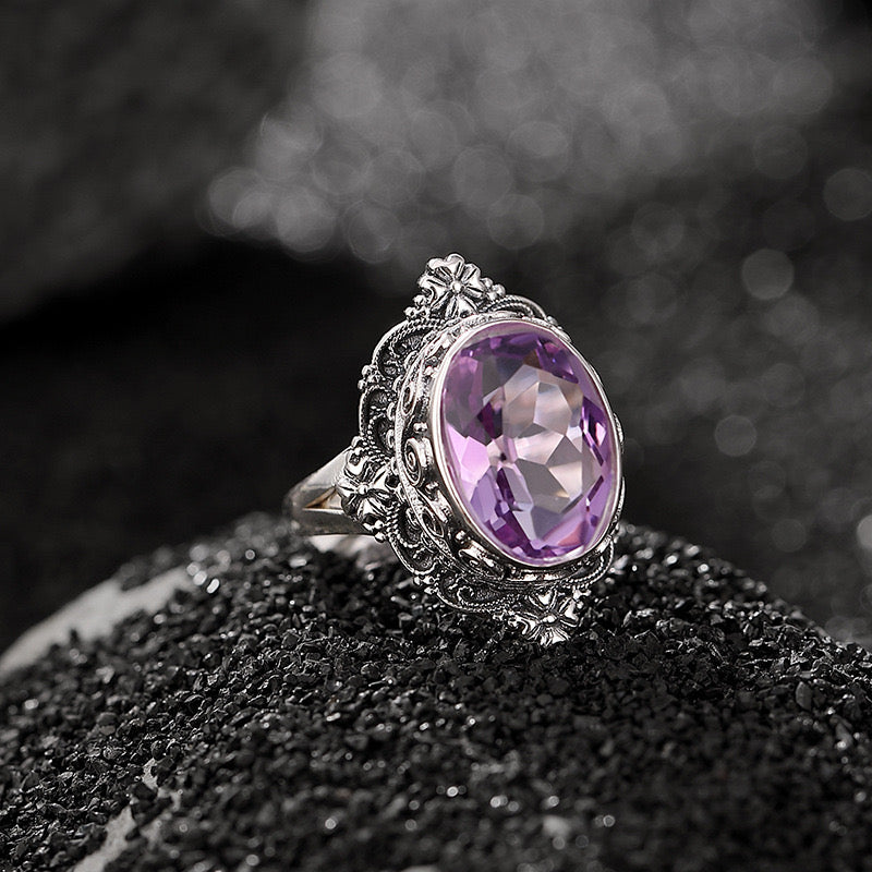 Bague Princesse Mystérieuse en argent ornée d'une grande améthyste ovale facetée, avec des détails floraux complexes sur le chaton.