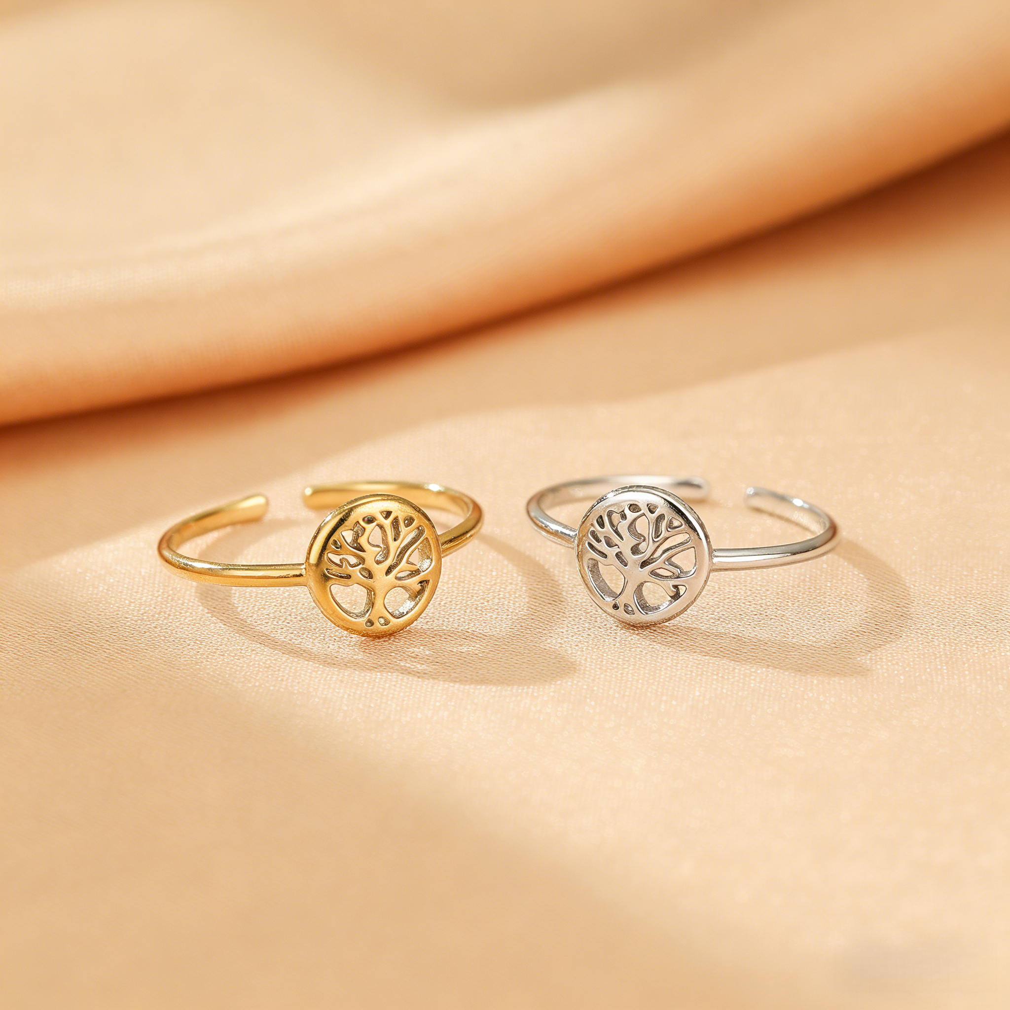 Bague Arbre de Vie "Essence Vitale" dorée et argentée, avec le symbole de l'arbre de vie ajouré, posée sur un fond satiné.