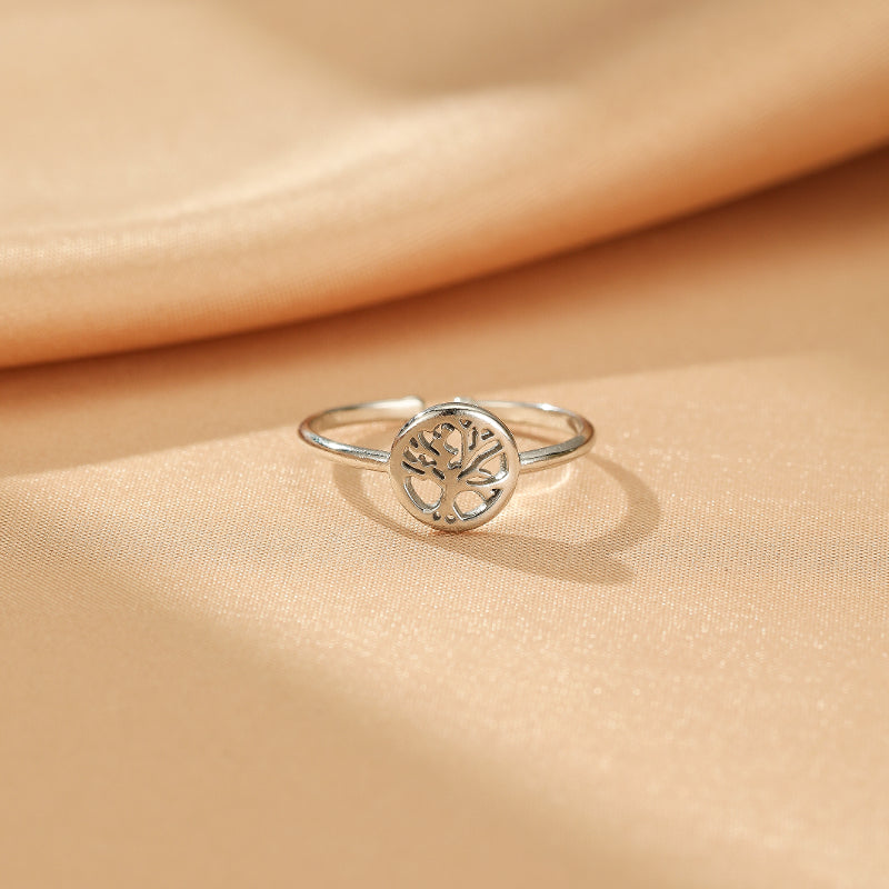 Bague Arbre de Vie – Essence Vitale, une bague en argent avec un motif d'arbre de vie ajouré au centre sur un fond satiné.