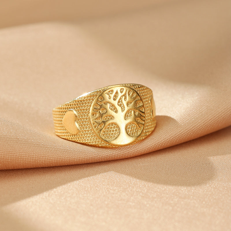 Bague dorée avec un motif d'arbre de vie gravé au centre, entouré de petits points et de deux cœurs de chaque côté.