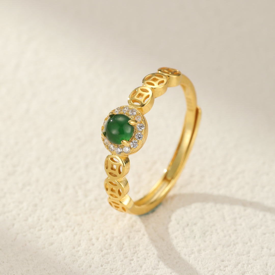 Bague ajustable en argent plaqué or avec une pierre de jade verte ronde entourée de zirconias et ornée de motifs de pièces chinoises traditionnelles.