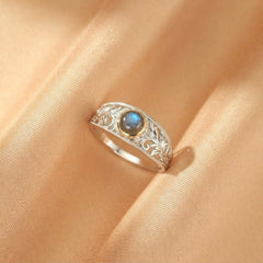 Bague en argent avec une labradorite bleue aux reflets irisés, sertie sur une monture ajourée aux motifs feuillage stylisé.