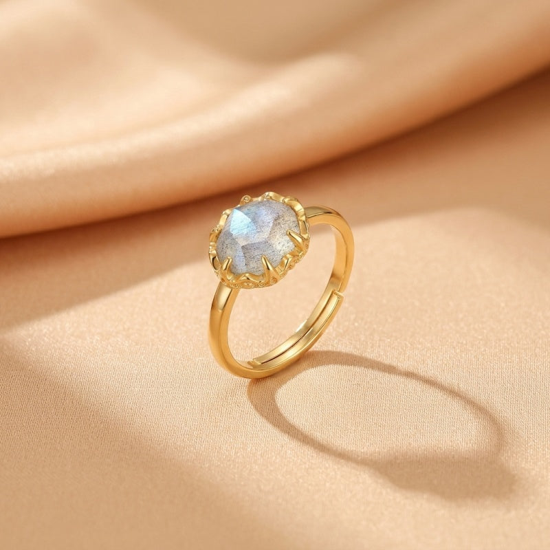 Bague en argent plaqué or avec une pierre de labradorite facettée aux reflets bleutés et gris, sertie sur une monture travaillée.