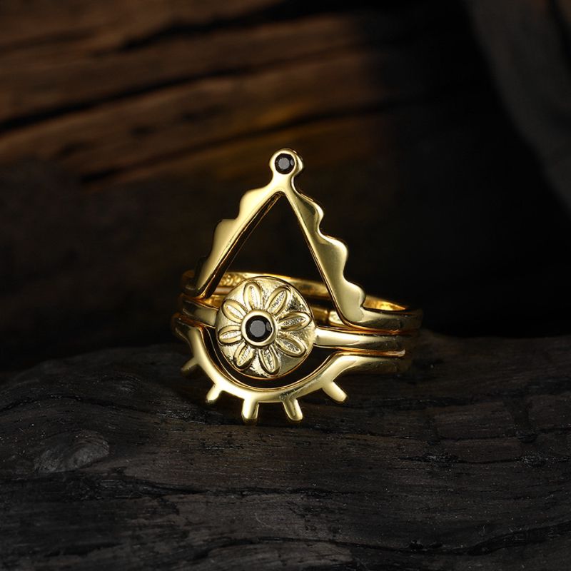 Bague triptyque en argent plaqué or avec un motif œil protecteur et une fleur centrale ornée d'une pierre noire.