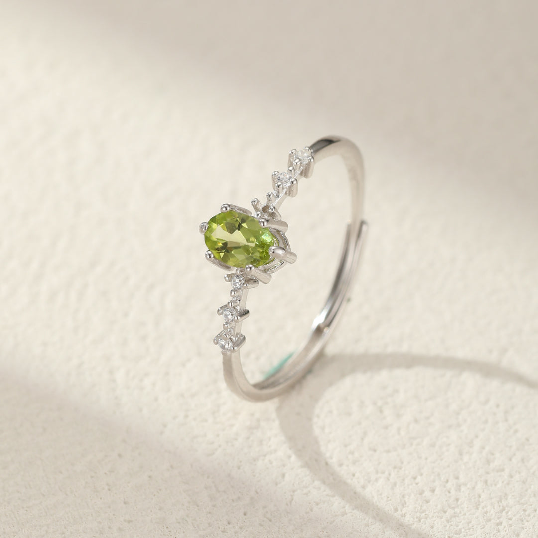 Bague en argent avec une pierre de péridot ovale verte et de petites pierres d'oxydes de zirconium serties sur une monture délicate.