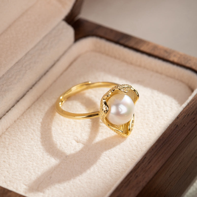 Bague en argent plaqué or sertie d'une perle blanche nacrée, ornée de petites pierres scintillantes sur le contour, présentée dans un écrin.