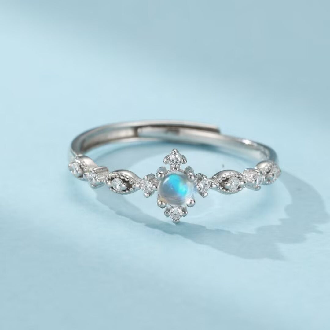 Bague en argent avec une pierre de lune bleue et des zircons, design délicat et scintillant.