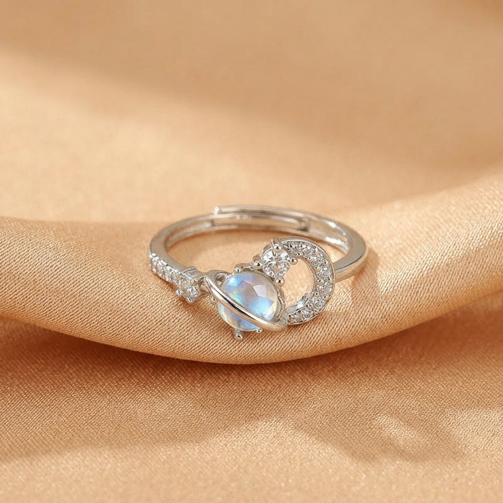 Bague en argent avec une pierre de lune bleutée et un design cosmique orné de petits cristaux.