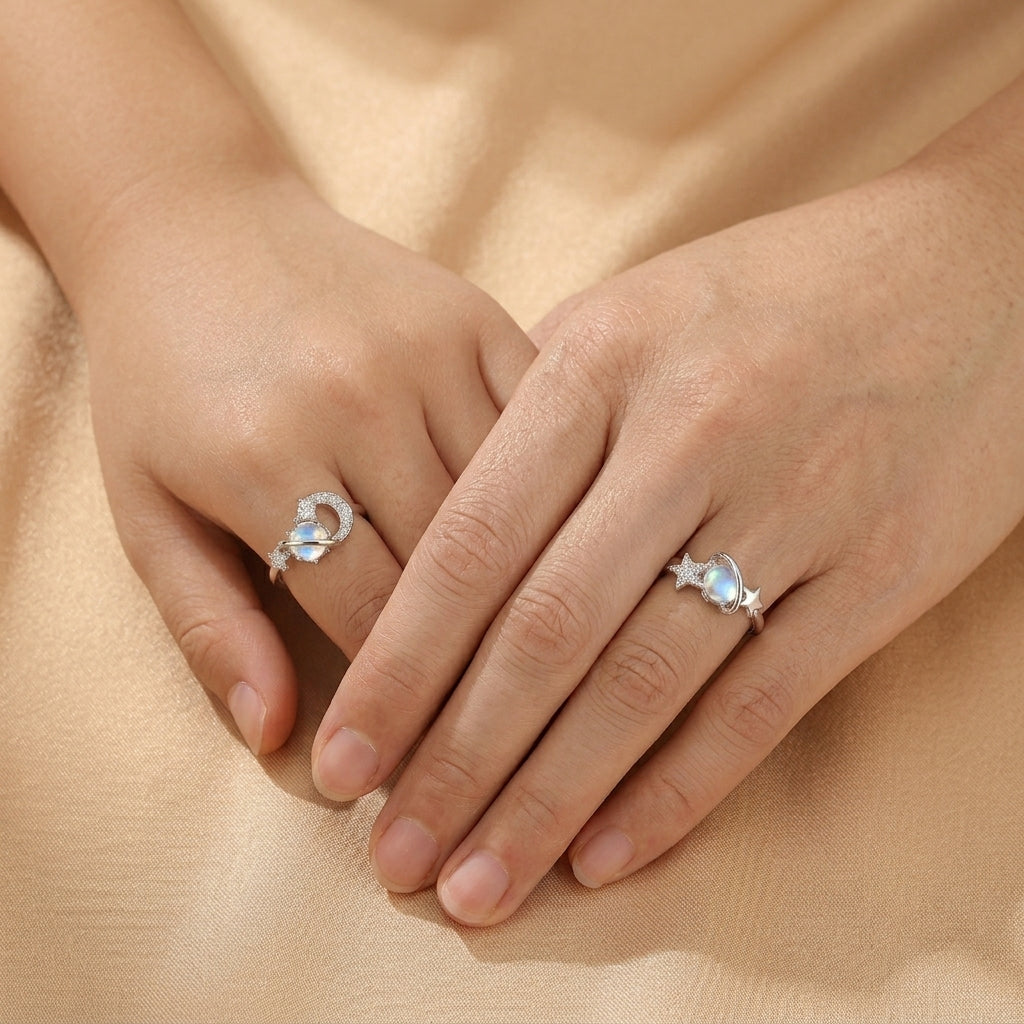 Deux bagues en argent ornées d'une pierre de lune bleue et de petits zircons, l'une en forme de croissant de lune et l'autre avec une étoile, portées sur les mains d'une femme.