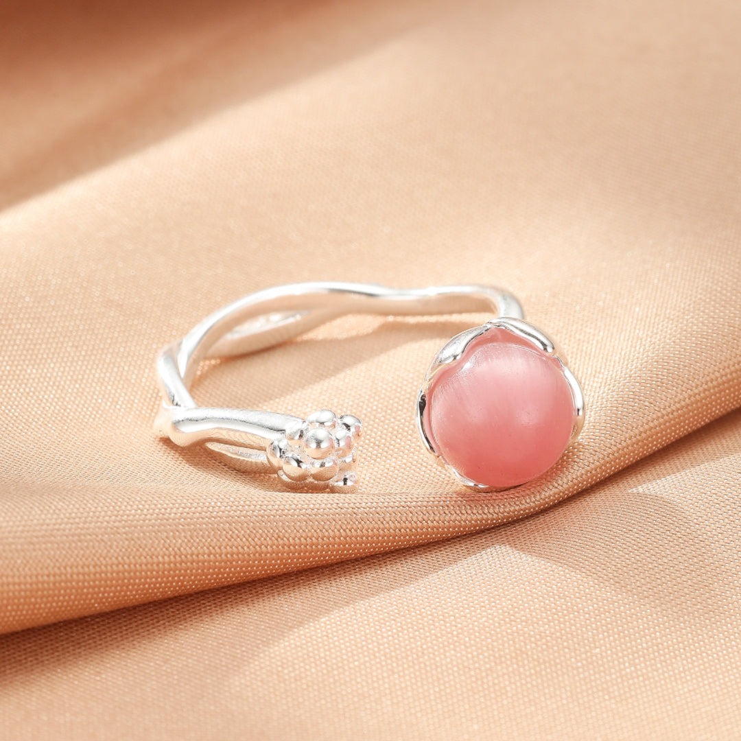 Bague ouverte en argent 925 avec une pierre de quartz rose ronde et une petite fleur stylisée.