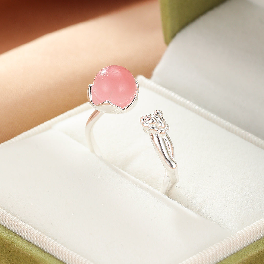 Bague ouverte en argent ornée d'un quartz rose cabochon rond, serti sur une monture en forme de fleur stylisée, et d'une petite tête de chat sur l'autre extrémité.