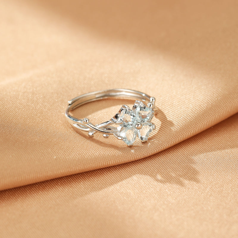 Bague en argent ajustable ornée d'un trèfle de topazes bleues claires et d'une branche torsadée, style bohème céleste.