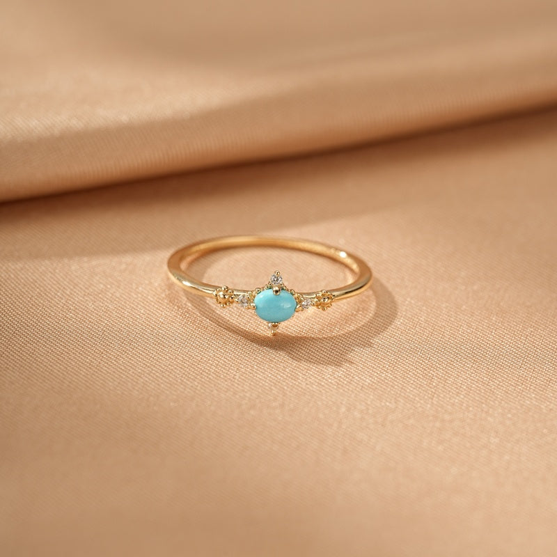 Bague fine en argent plaqué or 14k ornée d'une turquoise ovale et de petits diamants scintillants.