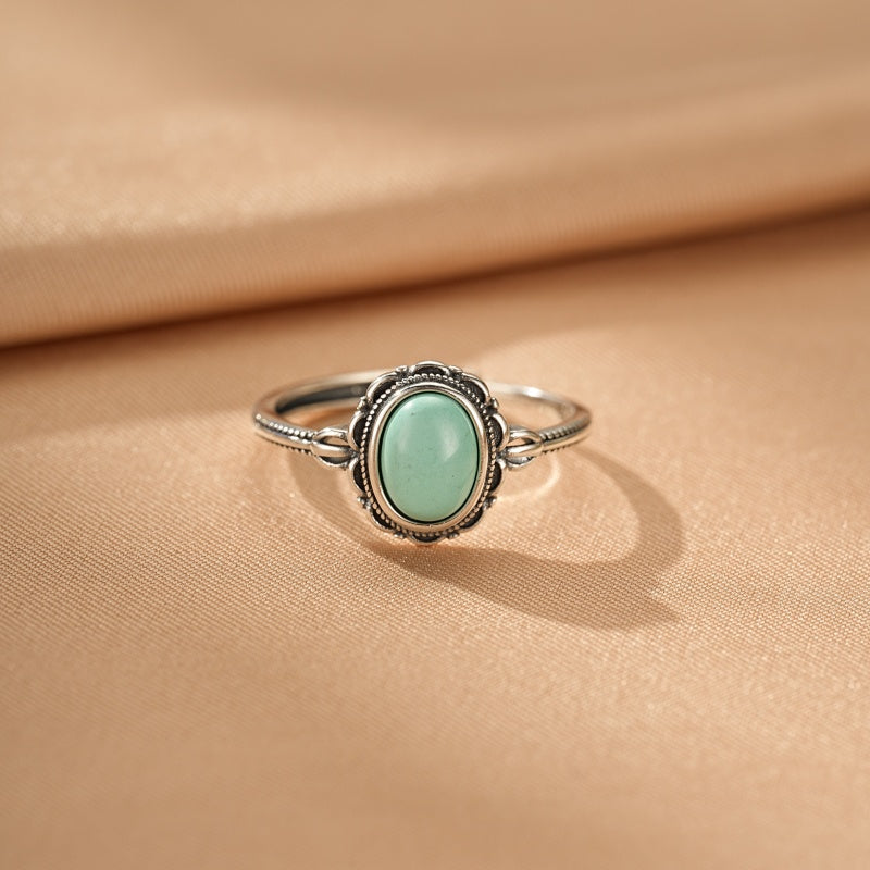 Bague en argent avec une pierre turquoise ovale sertie dans un entourage ouvragé, style bohème.