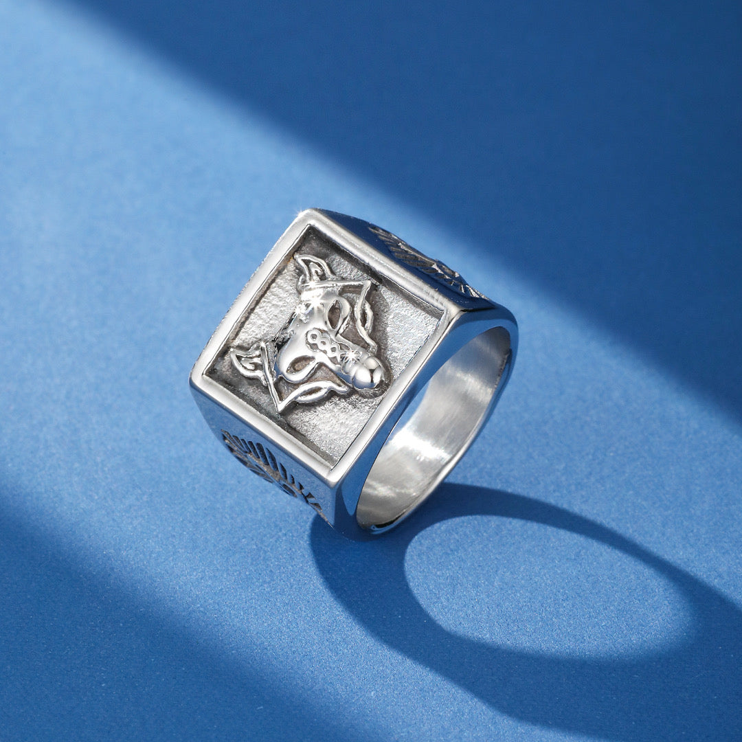Bague viking en argent avec une tête de loup stylisée en relief et des motifs runiques sur les côtés, sur fond bleu.