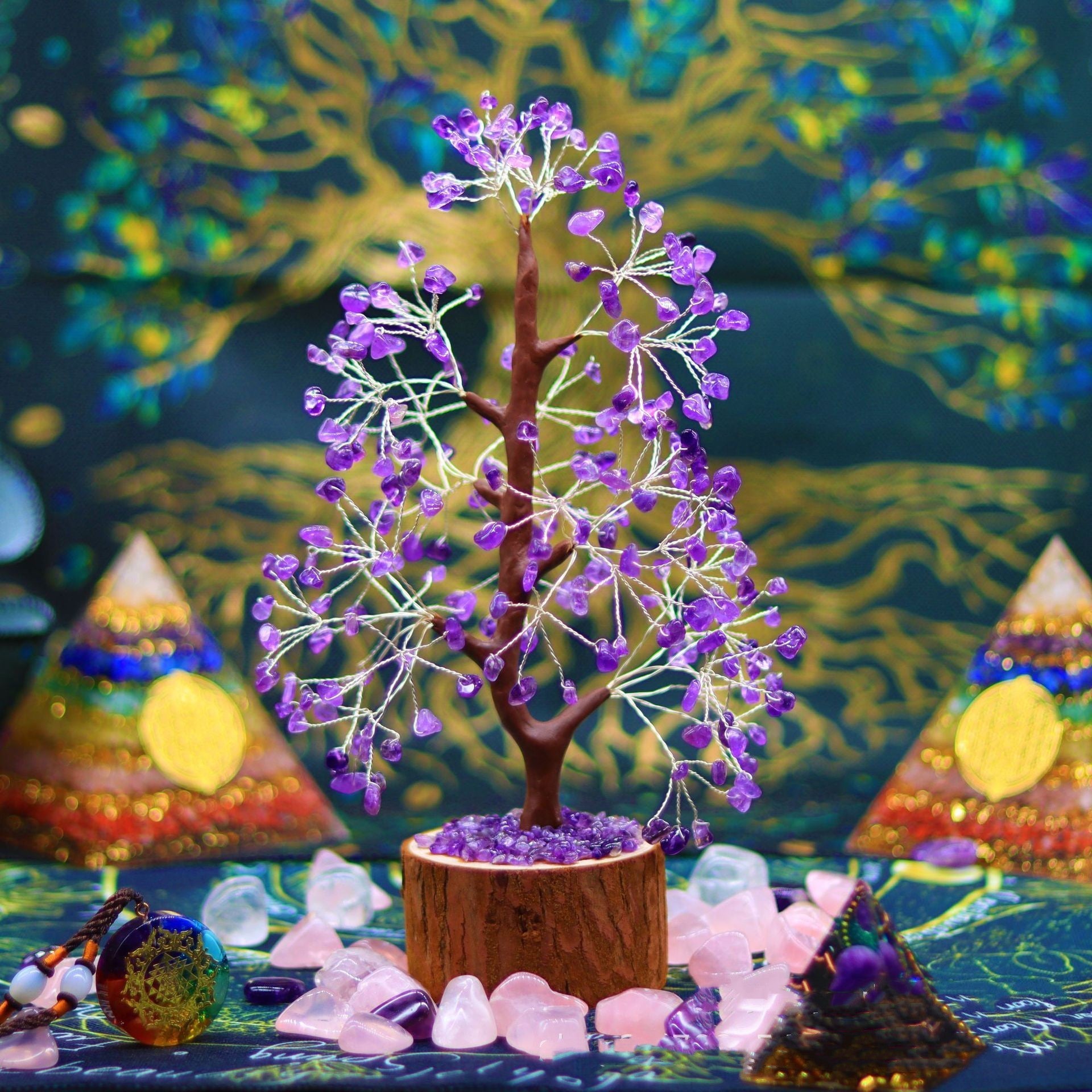 Arbre de Vie en pierres violettes de 7 chakras, monté sur un socle en bois, entouré de cristaux roses et d'une pyramide arc-en-ciel.