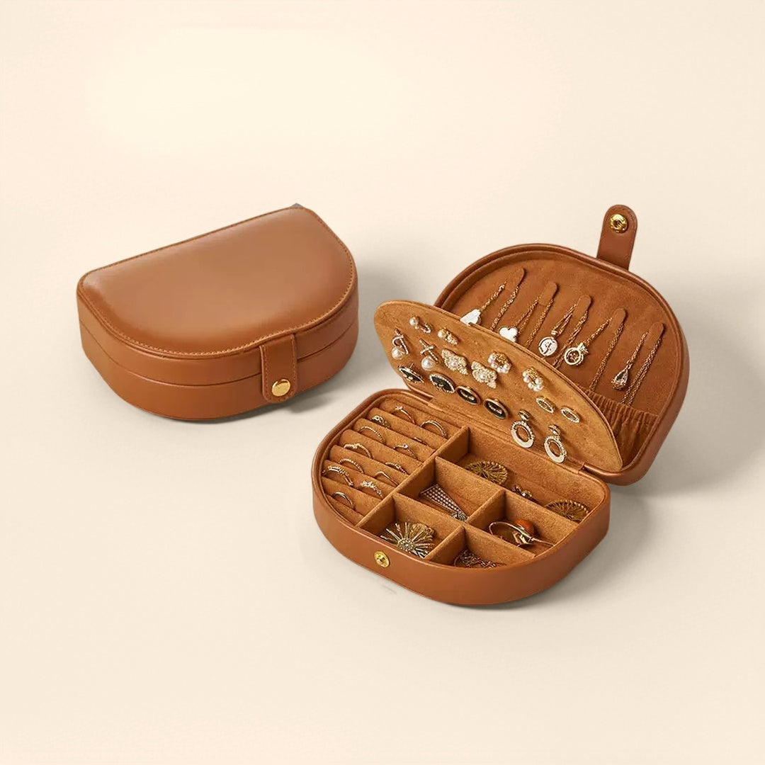 Boîte à bijoux de voyage en cuir marron, ouverte pour révéler un intérieur doublé de velours avec des compartiments pour bagues, boucles d'oreilles et colliers.