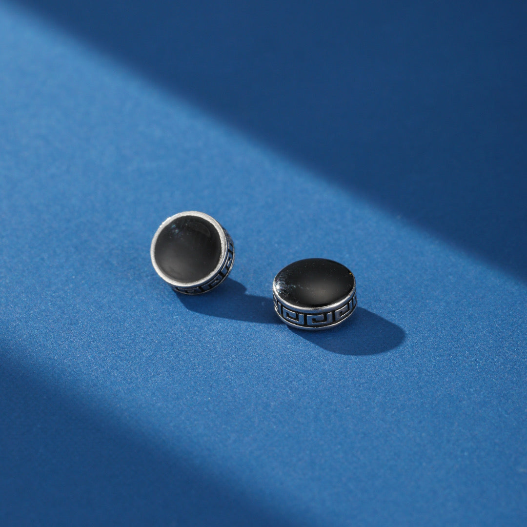 Homme portant une boucle d’oreille magnétique noire style cercle grec, vue de profil sur fond blanc