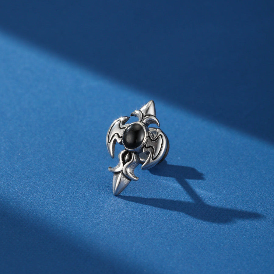 Boucle d'oreille homme argentée avec une pierre noire centrale et un design gothique inspiré des ailes de chauve-souris.