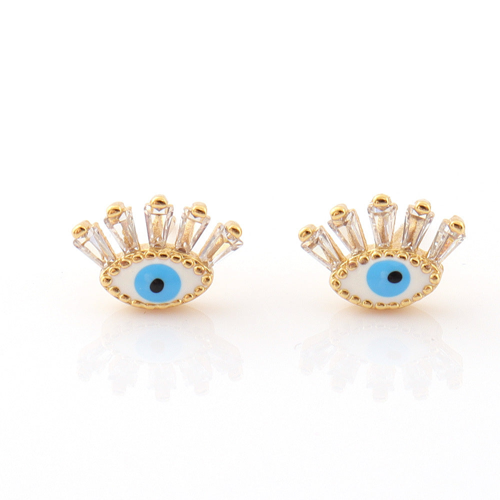 Boucles d’oreilles "Regard" Mauvais Œil en cristal blanc et or, ornées de petites pierres scintillantes.