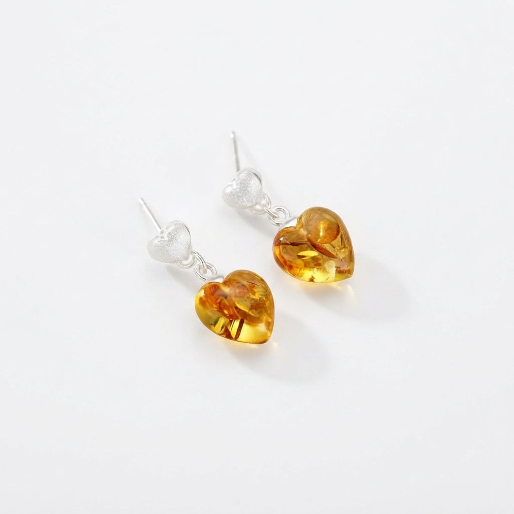 Boucles d'oreilles pendantes en argent avec cœurs en ambre véritable, design Cœur Solaire élégant sur fond blanc.