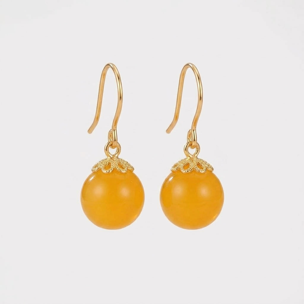 Paire de boucles d'oreilles pendantes avec perles d'ambre jaune rondes montées sur argent plaqué or, design élégant et minimaliste.