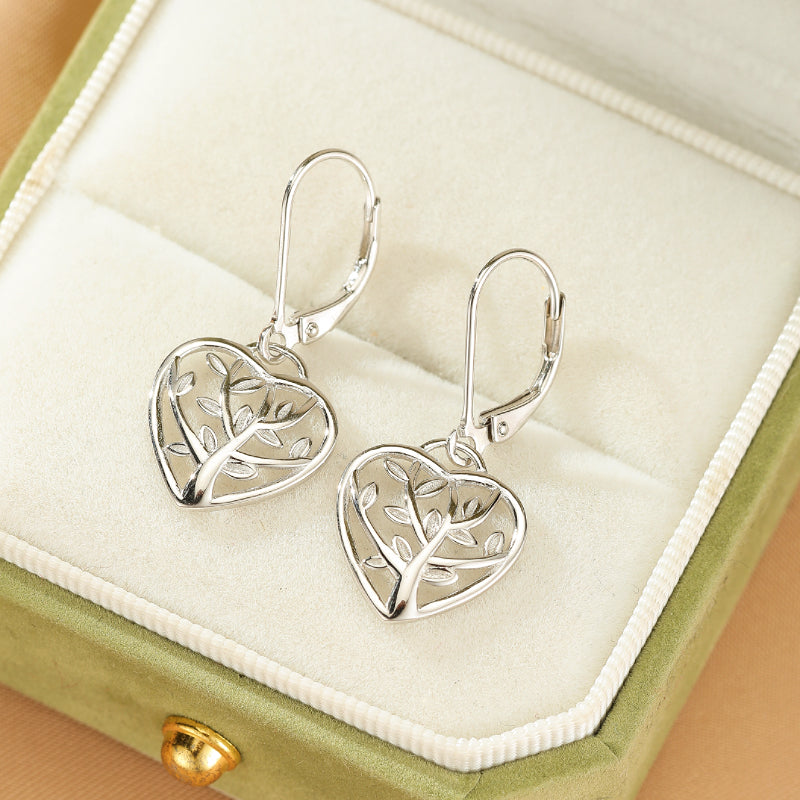 Boucles d'oreilles pendantes en forme de cœur ajouré avec motif d'arbre de vie, en argent 925, présentées dans une boîte à bijoux verte.
