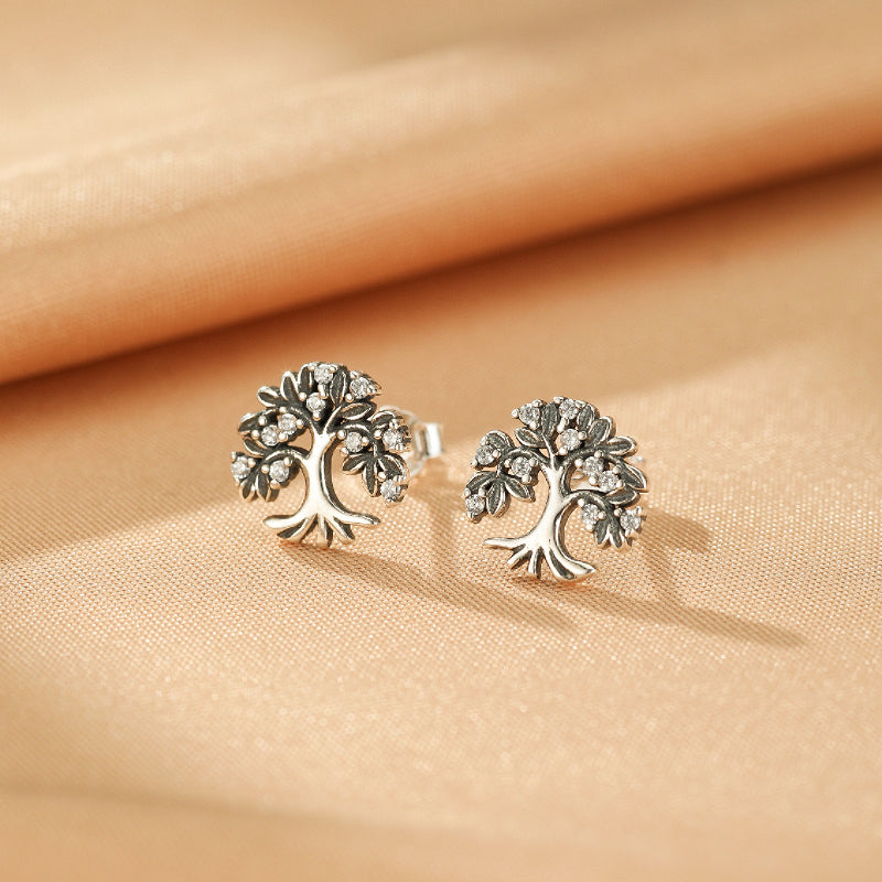 Boucles d'oreilles Arbre de Vie en argent 925 avec des zircons cubiques sertis sur les branches, présentées sur un fond satiné.