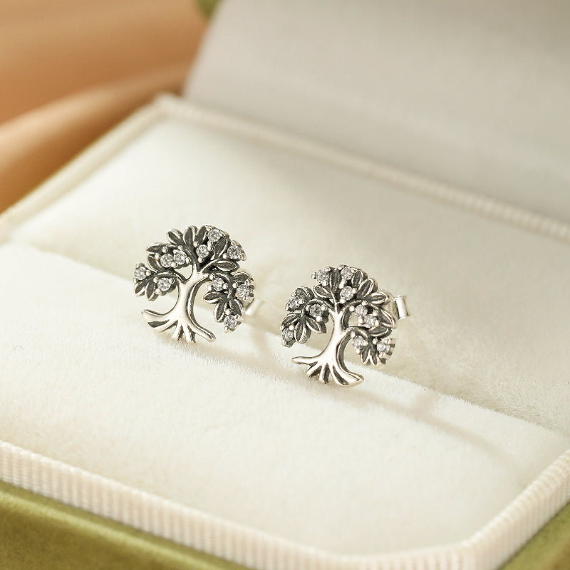 Paire de boucles d'oreilles en argent 925 représentant un arbre de vie stylisé avec des petites pierres incrustées dans les feuilles.