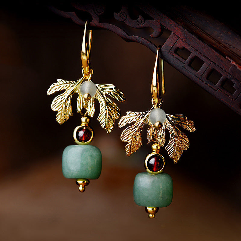 Boucles d'oreilles plaqué or avec pendentifs en forme de feuille dorée, ornées de perles d'aventurine verte, de grenats et de petites perles blanches.