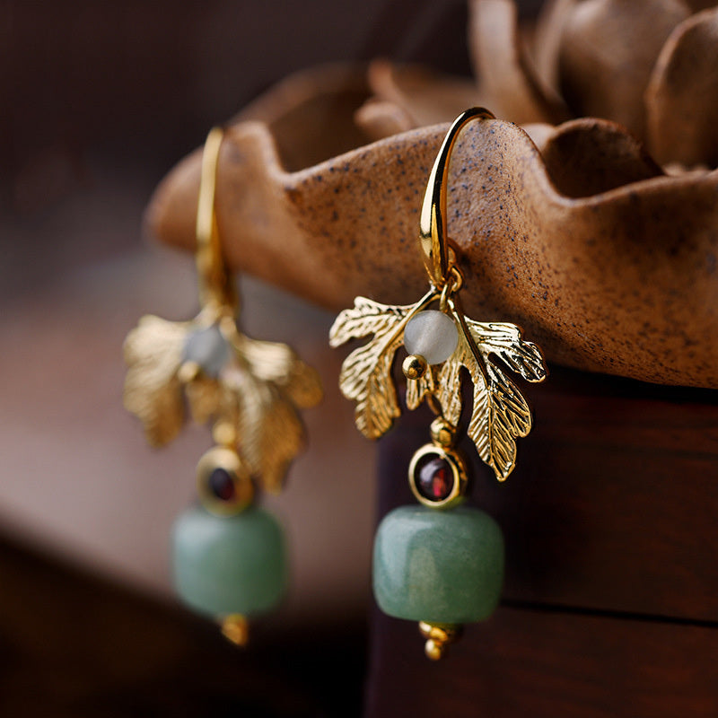 Boucles d'oreilles plaqué or avec pendentifs en forme de feuille, ornées d'une pierre verte et de grenats.