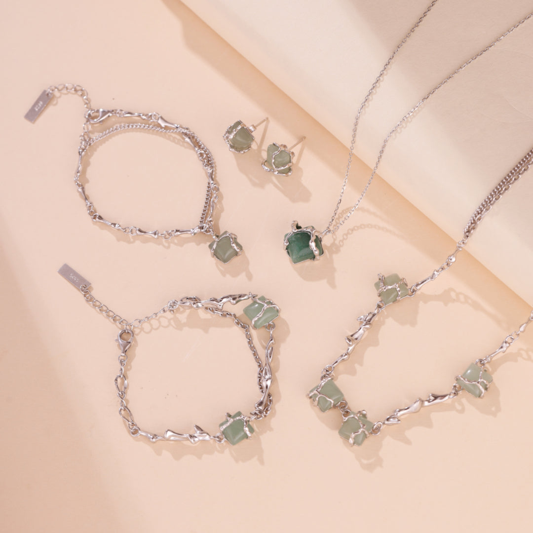 Ensemble de bijoux en argent sterling avec des pierres d'aventurine brute, comprenant des boucles d'oreilles, deux bracelets et deux colliers, le tout sur un fond clair.