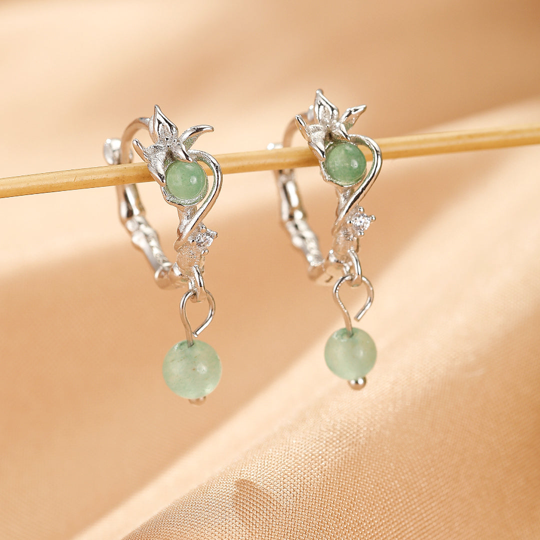 Boucles d’oreilles pendantes en argent ornées d'une pierre d'aventurine verte et d'un motif de rameau fleuri.