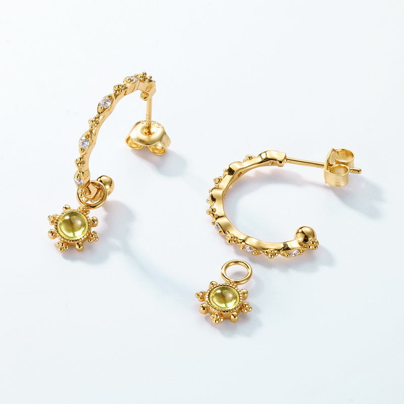 Boucles d’oreilles créoles plaqué or ornées de péridots et de zirconiums, avec un pendentif soleil amovible.