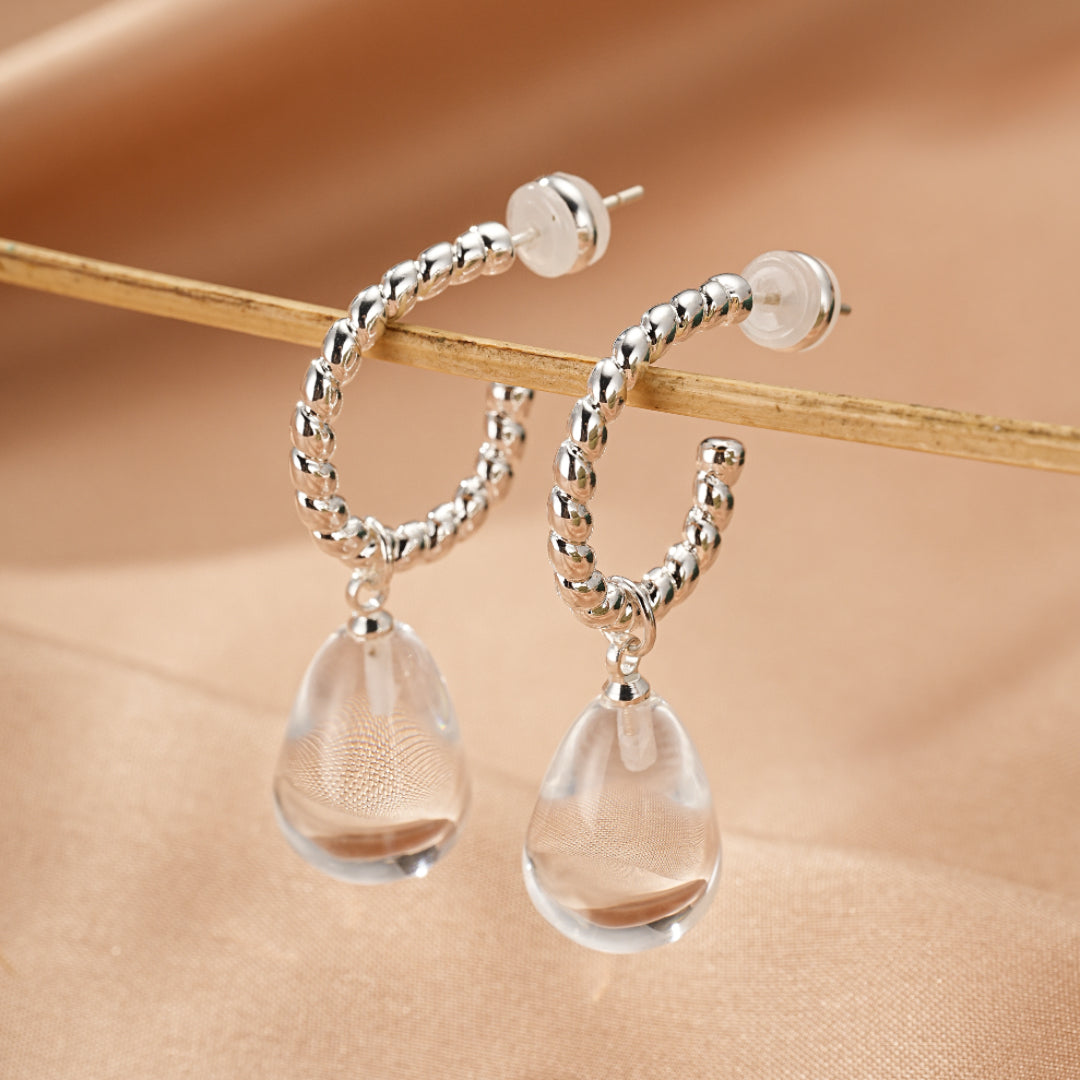 Paire de créoles torsadées en argent avec pendentifs en forme de goutte de cristal de roche transparent.