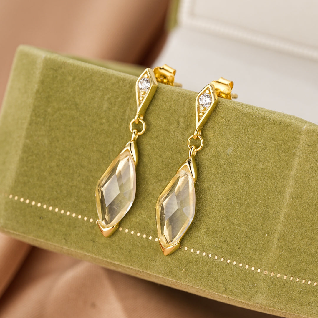 Boucles d'oreilles pendantes plaqué or 14K avec cristal de roche taillé en forme de losange et petites pierres d'imitation diamant.