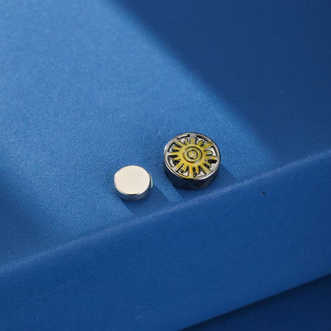 Gros plan sur les boucles d'oreilles magnétiques homme duo cosmique, montrant les détails du soleil et de l'étoile.
