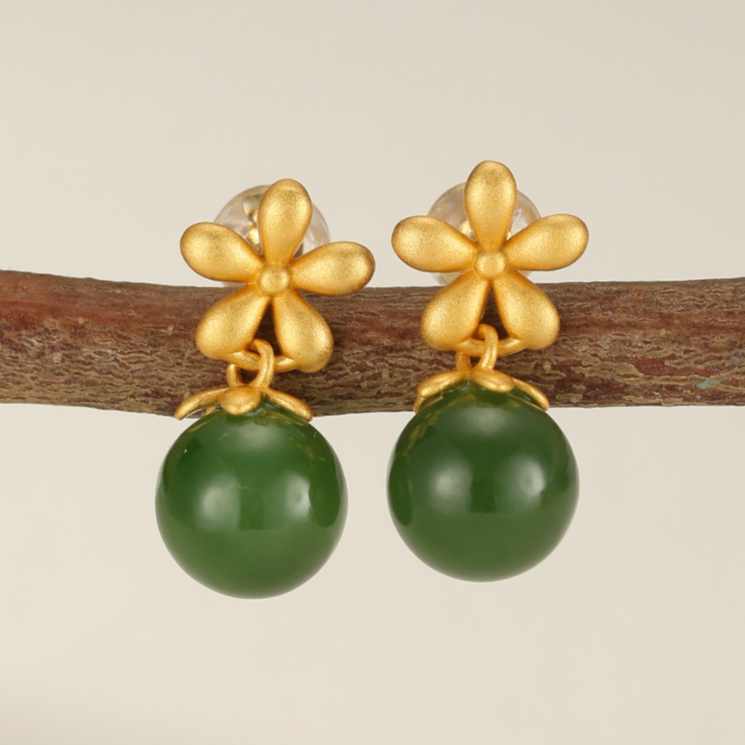 Boucles d'oreilles pendantes en argent plaqué or avec une petite fleur dorée et une perle ronde en jade vert.