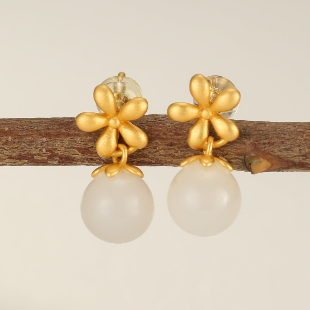 Paire de boucles d'oreilles pendantes en argent plaqué or ornées d'une petite fleur dorée et d'une perle ronde blanche nacrée.