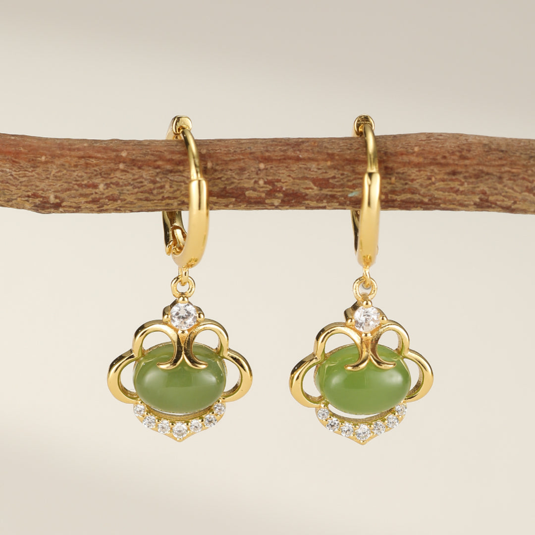 Boucles d'oreilles pendantes en argent plaqué or ornées de jade vert ovale et de zircons cubiques scintillants, suspendues à une branche.