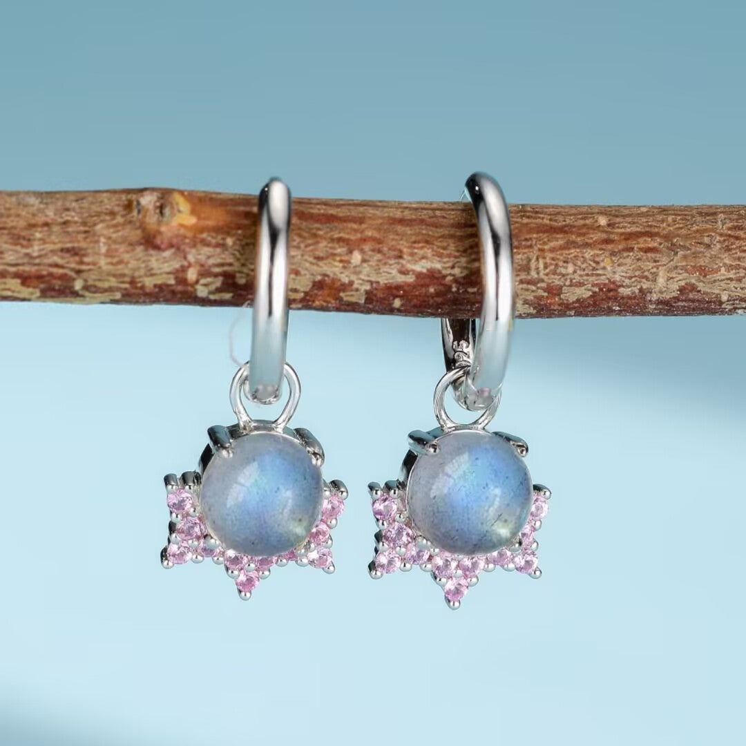Une paire de boucles d'oreilles en argent plaqué or avec des pierres de labradorite bleues et des petites pierres roses disposées en forme d'étoile.