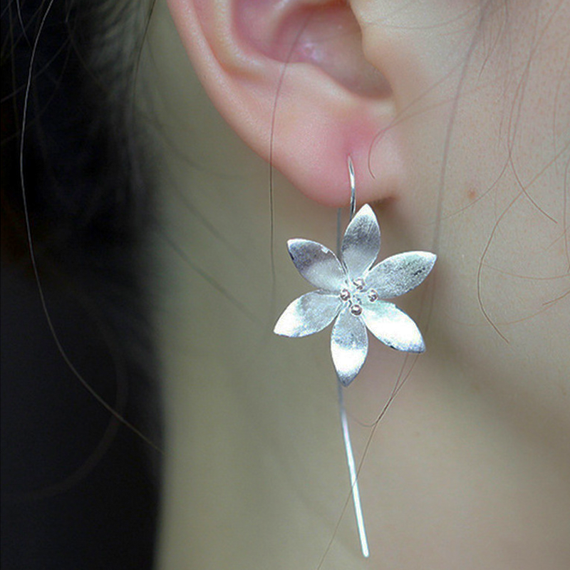 Boucle d'oreille pendant argent motif fleur de lotus éclose avec fil fin et petites perles au centre, portée à l'oreille.