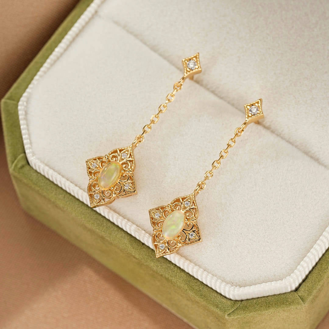 Boucles d'oreilles pendantes en argent plaqué or 10K avec opale ovale et diamants incrustés dans un écrin vert.